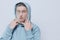 tortured, suffering from problems, a man with a mesh on his face stands in a light blue hoodie on a light background and