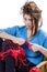 Tortured young girl in a sweater sits on a chair with a red ball of yarn and knitting a scarf and Spitz. Tired. White background.