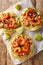 Tostadas with juicy shrimp, creamy avocado guacamole and tangy salsa closeup on the wooden table. Vertical top view