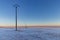 Totally frozen winter landscape in shades of blue and with electric poles in perspective