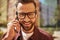 Always in touch. Portrait of cheerful and handsome bearded man in eyeglasses talking by phone and smiling while standing