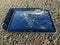 Touch screen tablet with broken screen lying on asphalt road
