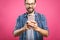 Always in touch. Smiling young man holding smart phone and looking at it. Portrait of a happy man using mobile phone isolated over