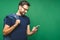 Always in touch. Smiling young man holding smart phone and looking at it. Portrait of a happy man using mobile phone isolated over