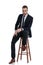 Tough businessman leaning on his leg, sitting on a stool