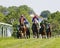 Tough fight between many colorful jockeys riding arabian race horses, trees in the background