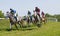 Tough fight between many jockeys riding arabian race horses, trees in the background