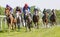 Tough fight between many jockeys riding arabian race horses, trees in the background