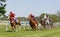 Tough fight between many jockeys riding arabian race horses, trees in the background