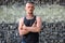 Tough guy standing thoughtful in front of a wall of stones