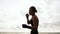 Tough pretty woman shadow boxing. Beautiful female boxer training by the sea on the beach in the morning, throwing