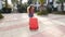Toung woman with a red suitcase running on a resort
