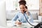 Tour agent sitting at table in office talking with client on phone taking notes cheerful