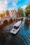 Tour boat at famous Dutch canal on a sunny day, traditional Dutch bridges, medieval houses. Amsterdam Holland