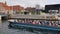 Tour boat which full of tourists move into Frederiksholms canal and background of waterfront and Det Kongelige library.