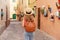 Tourism in Alghero, Sardinia. Back view of traveler girl walking in picturesque cozy narrow alley of Alghero town, Italy. Young