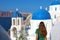 Tourism in Greece. Back view of traveler tourist girl visiting the famous white village with blue domes of Oia, Santorini.