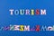 TOURISM word on blue background composed from colorful abc alphabet block wooden letters, copy space for ad text