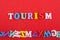 TOURISM word on red background composed from colorful abc alphabet block wooden letters, copy space for ad text