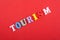 TOURISM word on red background composed from colorful abc alphabet block wooden letters, copy space for ad text