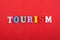 TOURISM word on red background composed from colorful abc alphabet block wooden letters, copy space for ad text