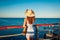 Tourism. Young woman traveler admiring landscape on pier by Red sea. Summer fashion