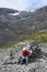 A tourist with a backpack sits on a stone on a mountainside. Rest during the climb to mountain pass. The Khibiny, Russia