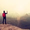 Tourist with backpack takes photos with smart phone of rainy vally. Dreamy foggy valley below