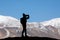 Tourist with backpack taking a photo on the rock in the beautiful mountains view of snowy Tso Moriri Lake in Leh Ladakh india