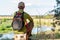 A tourist with a backpack on a wooden stump by the river. Tourist resting on a tree stump