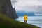 Tourist with backpack in yellow jacket looks at Witches Finger cliffs