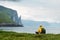 Tourist with backpack in yellow jacket looks at Witches Finger cliffs