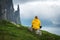 Tourist with backpack in yellow jacket looks at Witches Finger cliffs