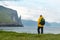 Tourist with backpack in yellow jacket looks at Witches Finger cliffs