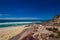 Tourist with backpacks on a large stone and enjoying Sea View. Ben Boyd national park, Australia