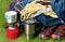 Tourist bag with shoes, on a green lawn, next to a red gas burner and a mug