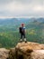 Tourist with big backpack stand on rocky view point and watching to colorful autumnal country