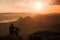 Tourist in black wind jacket sit on sharp rock and watch into colorful misty valley bellow. Sunny spring daybreak in rocky