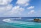 Tourist boat rounding a rocky cape with a lighthouse in the Maldives