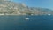 A tourist boat sails in the middle of the Bay of Kotor, in front of it is a cozy little town, big yacht and small boat