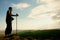 Tourist with camera on neck and poles in hands on peak of rock. Dreamy landscape bellow in a beautiful valley below