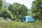 Tourist camp with lots of tents in the woods. Tourist tent in the green fores, blue sky and sun