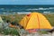 Tourist camping on the sand by the sea, yellow tent on the beach