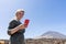 Tourist Caucasian pretty teen lady in el Teide with green dress, look to her smart phone searching for information in internet in