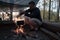 Tourist cooking dinner over a campfire at the camp. Man stirring food in a bowler, which hangs over a fire, on a summer