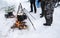 Tourist cooking food on bonfire, cooking on snow in winter. Preparation food for breakfast, lunch and dinner