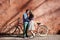 Tourist couple, bearded man and blond woman on tandem bicycle on background of red crackled wall.