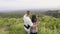 Tourist couple looking on mountain and highlands covered green forest on skyline background. Traveling couple embracing