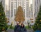 Tourist couple posing before the 2019 iconic Rockefeller Christmas Tree in Rockefeller Plaza, New York City