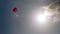 Tourist does parasailing on red parachute in clear blue sky